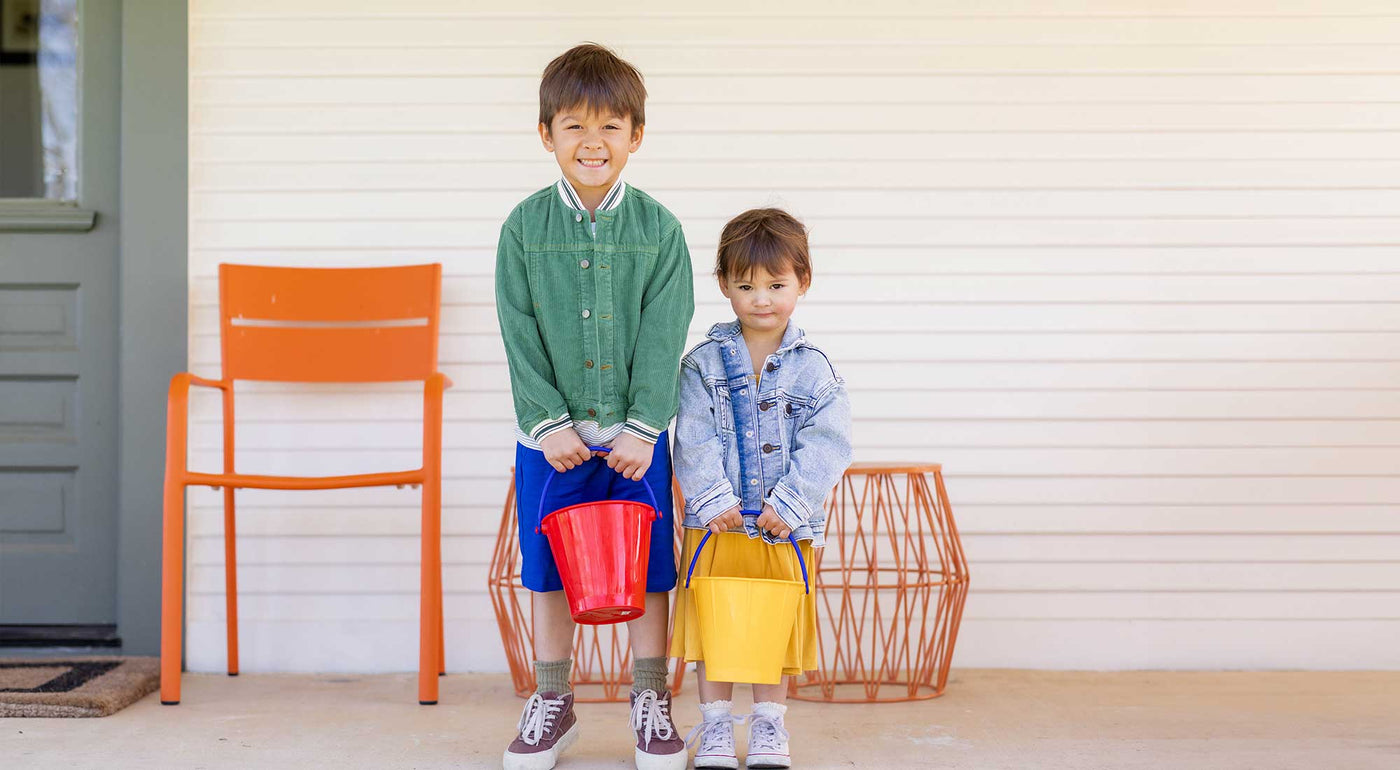 two kids standing with Easter buckets in red and yellow.