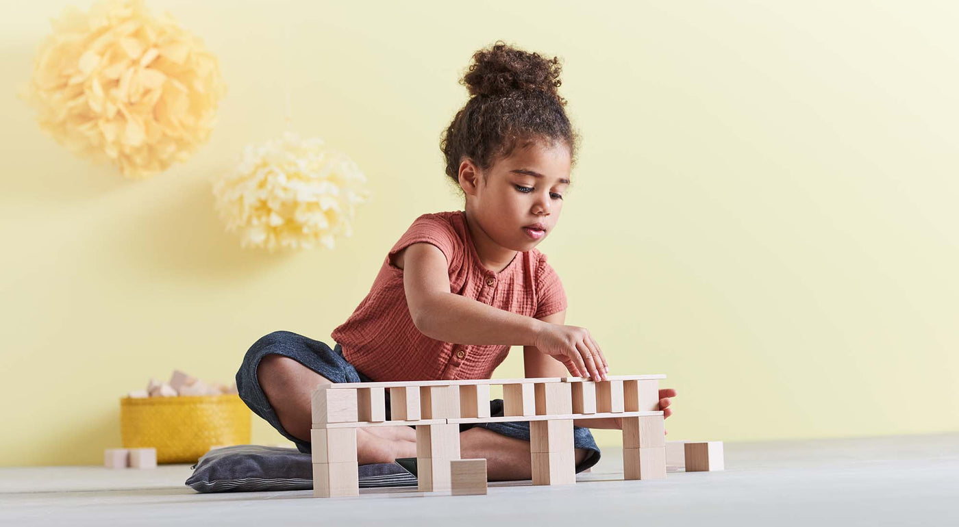A girl is playing with wooden blocks.