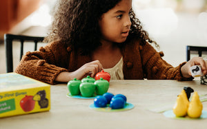 Girl sitting at table playing HABA My Very First Games First Orchard