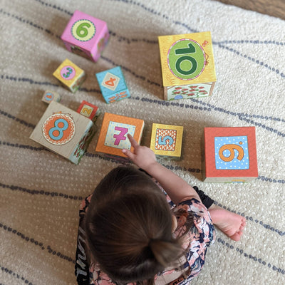 Child playing with On the Farm Stacking and Nesting Cubes on the floor