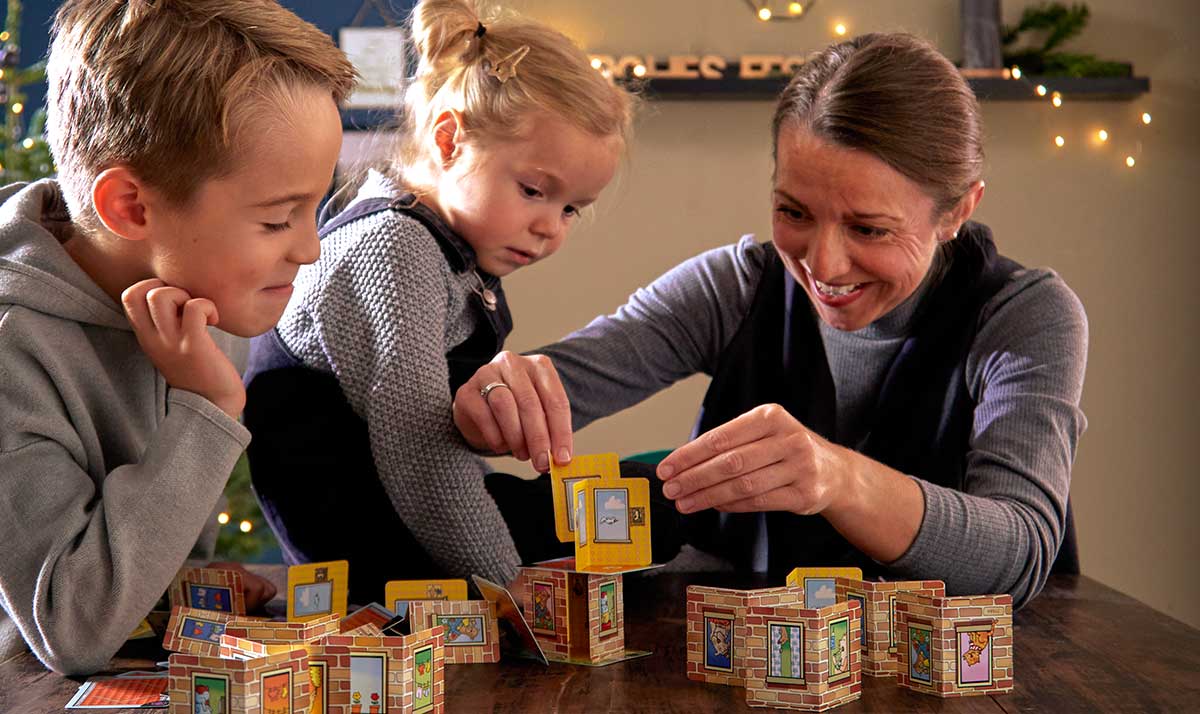 A family sits playing a Rhino Hero board game.