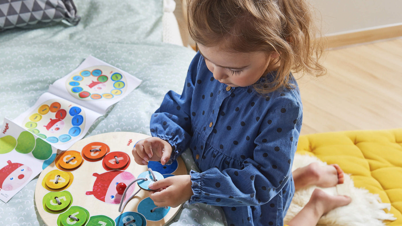 Kid playing with Rainbow Caterpillar Threading game