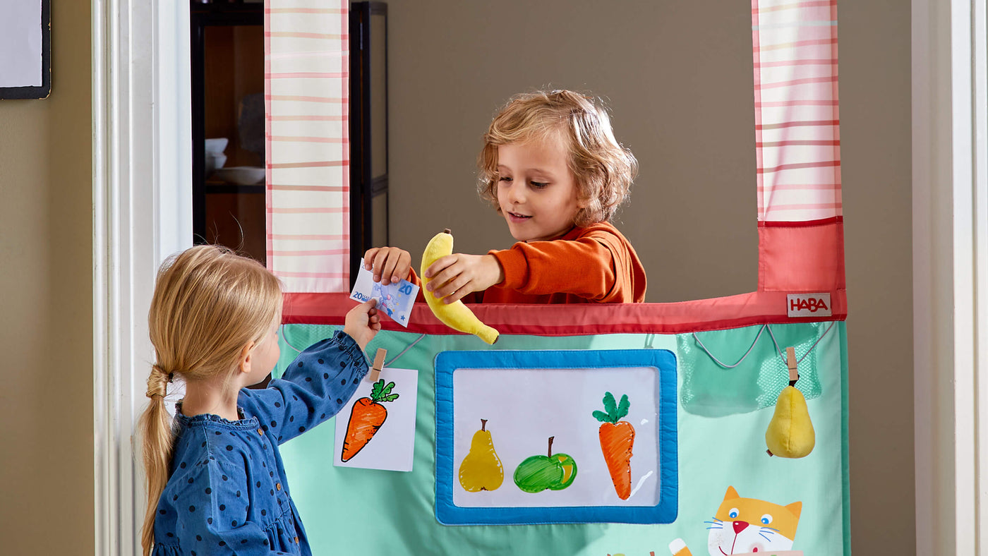 Kid selling play banana to another child through the HABA Doorway Play Store 