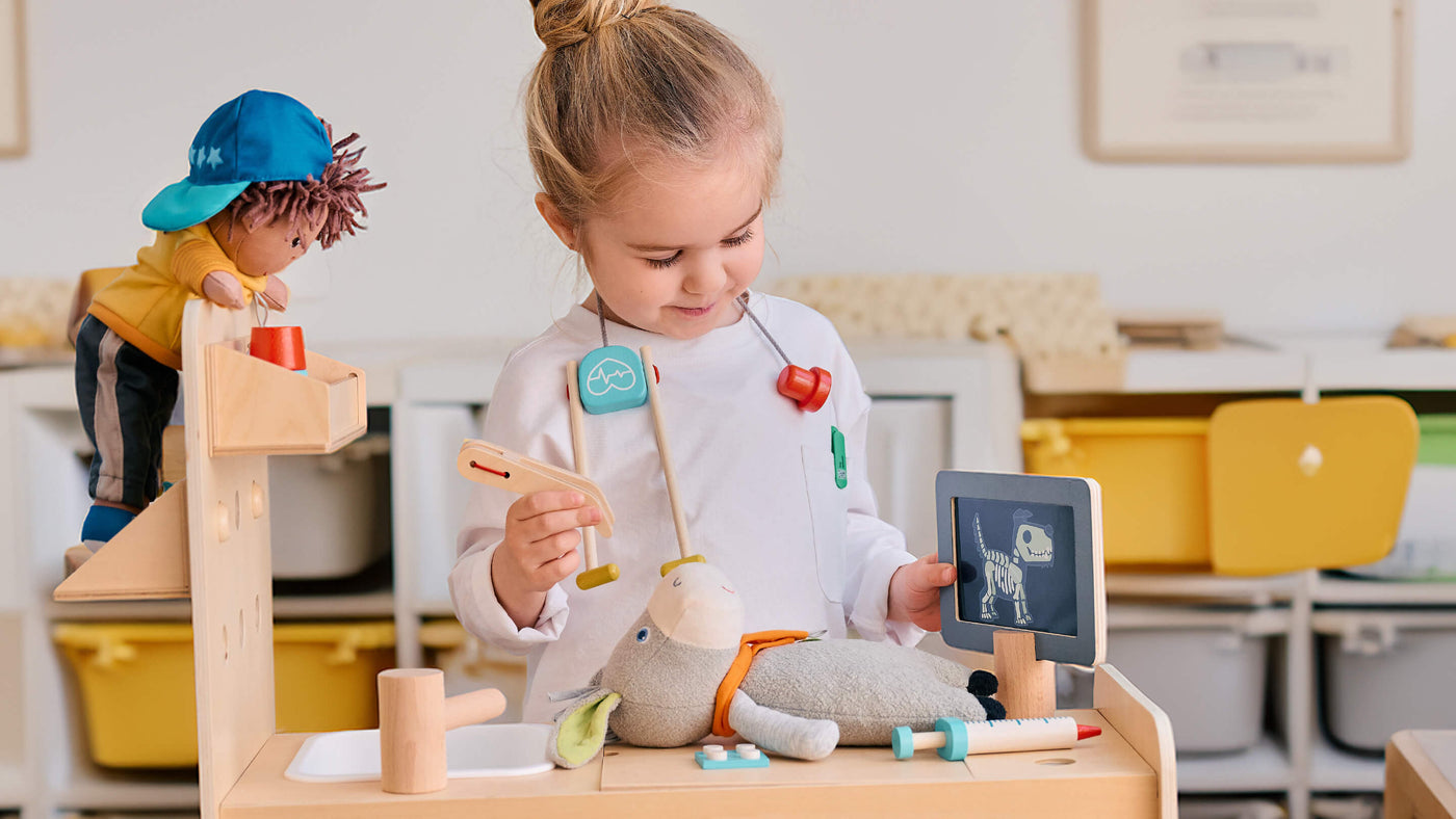 Child playing veterinarian with a toy donkey and medical tools in the HABA Creative Play 3 in 1 Play Kitchen, Store and Workshop
