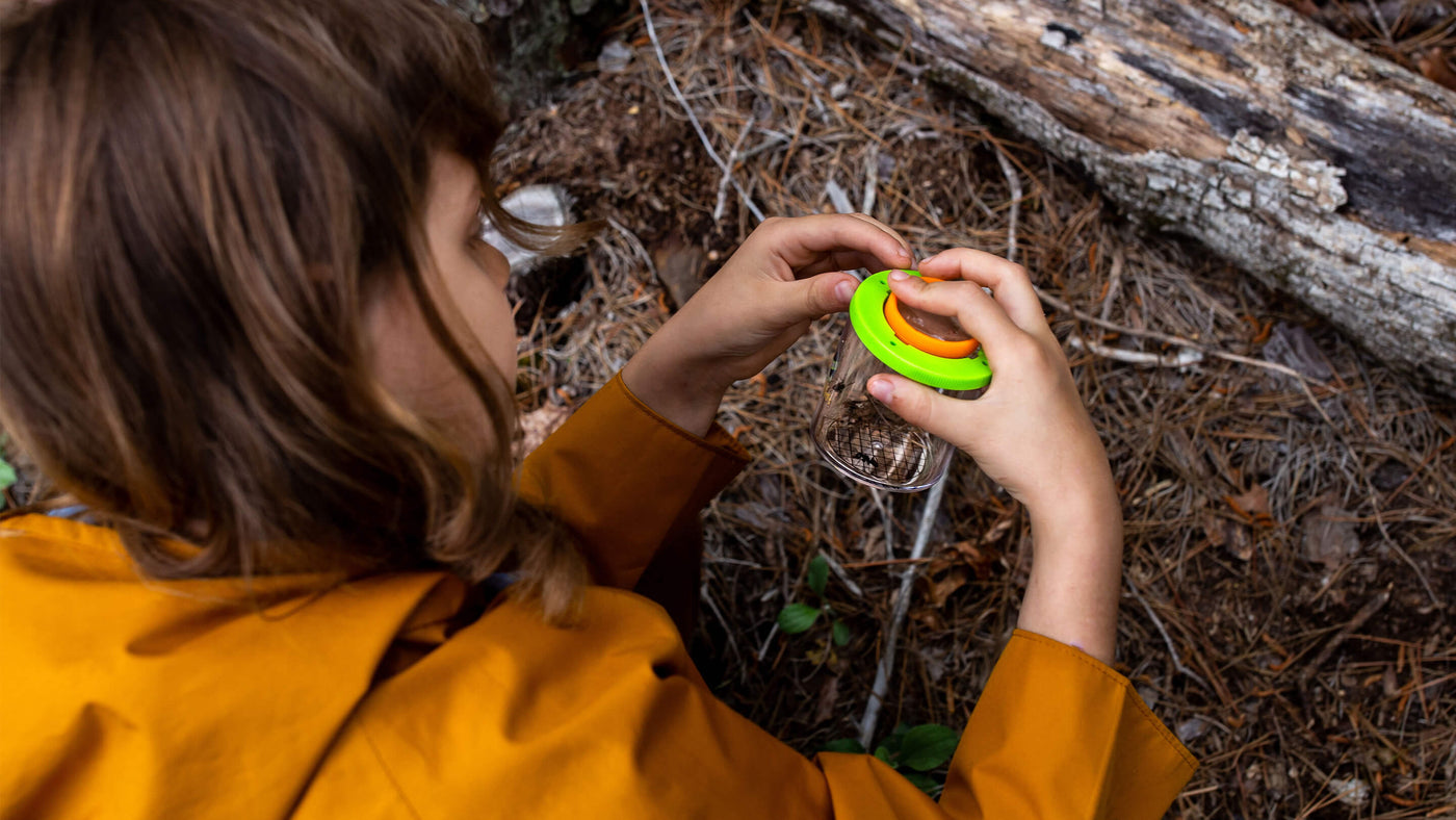 Girl in a jacket outside holding a Terra Kids Beaker Magnifier with ants inside