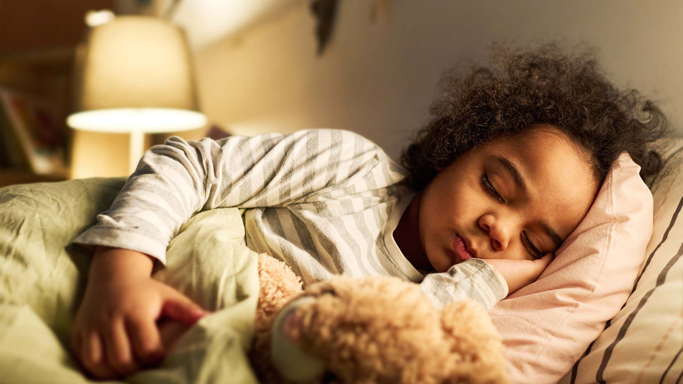 Child sleeping in bed with toy at night