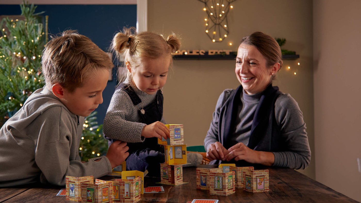 family gathered around a table during Christmas playing Rhino Hero Stacking Cards Game