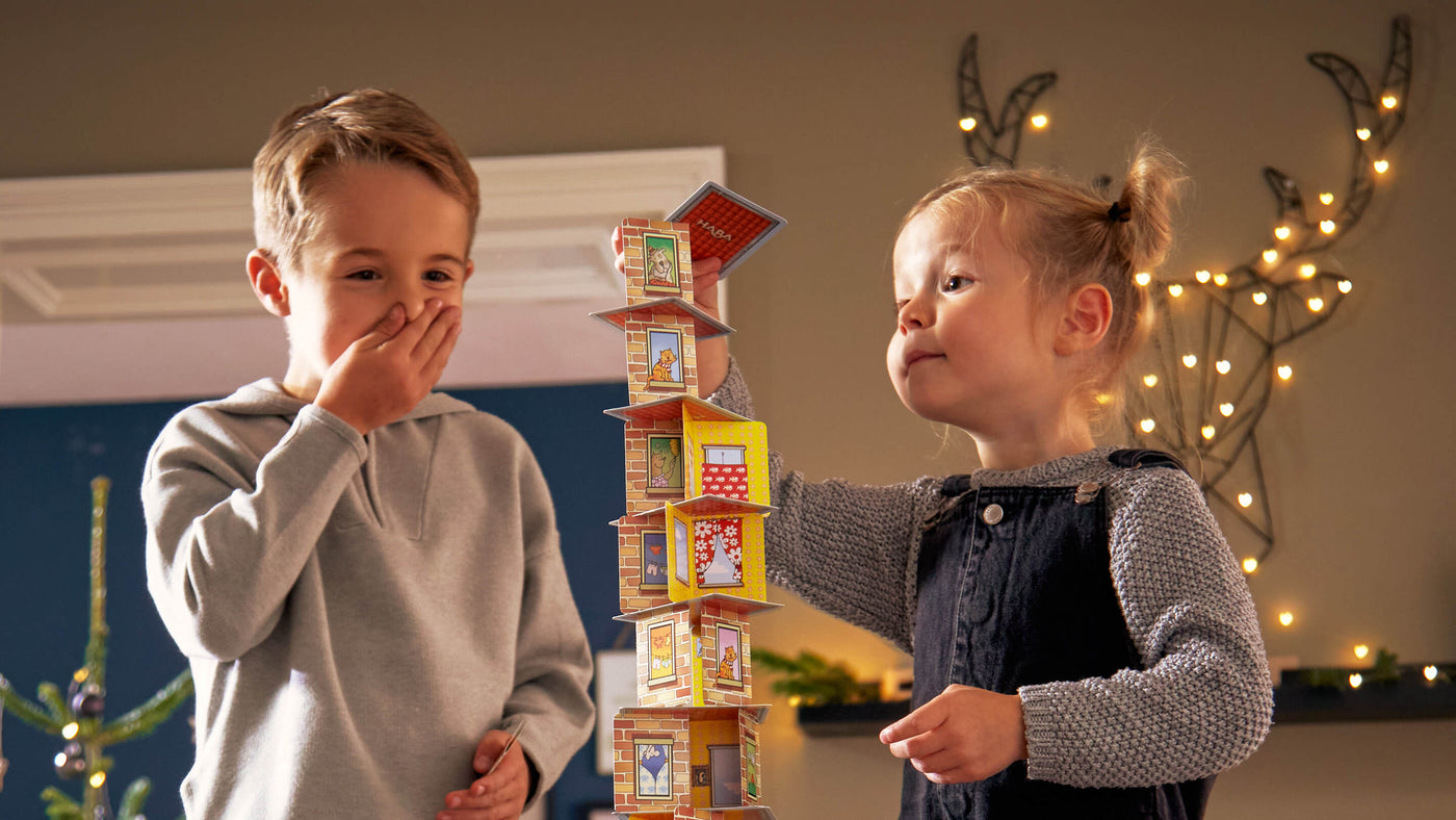Two kids playing Rhino Hero in a holiday scene