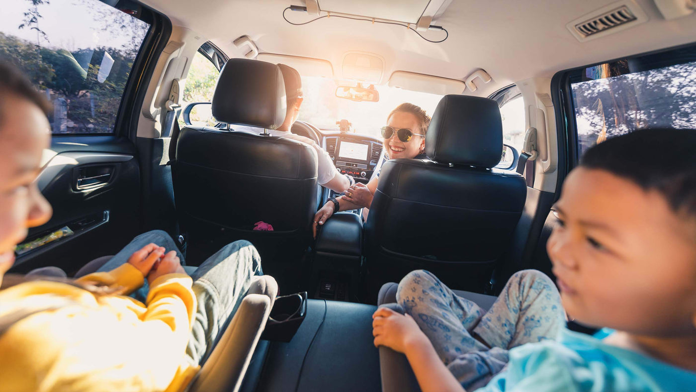 Happy family of four in car, woman turned around to look at kids