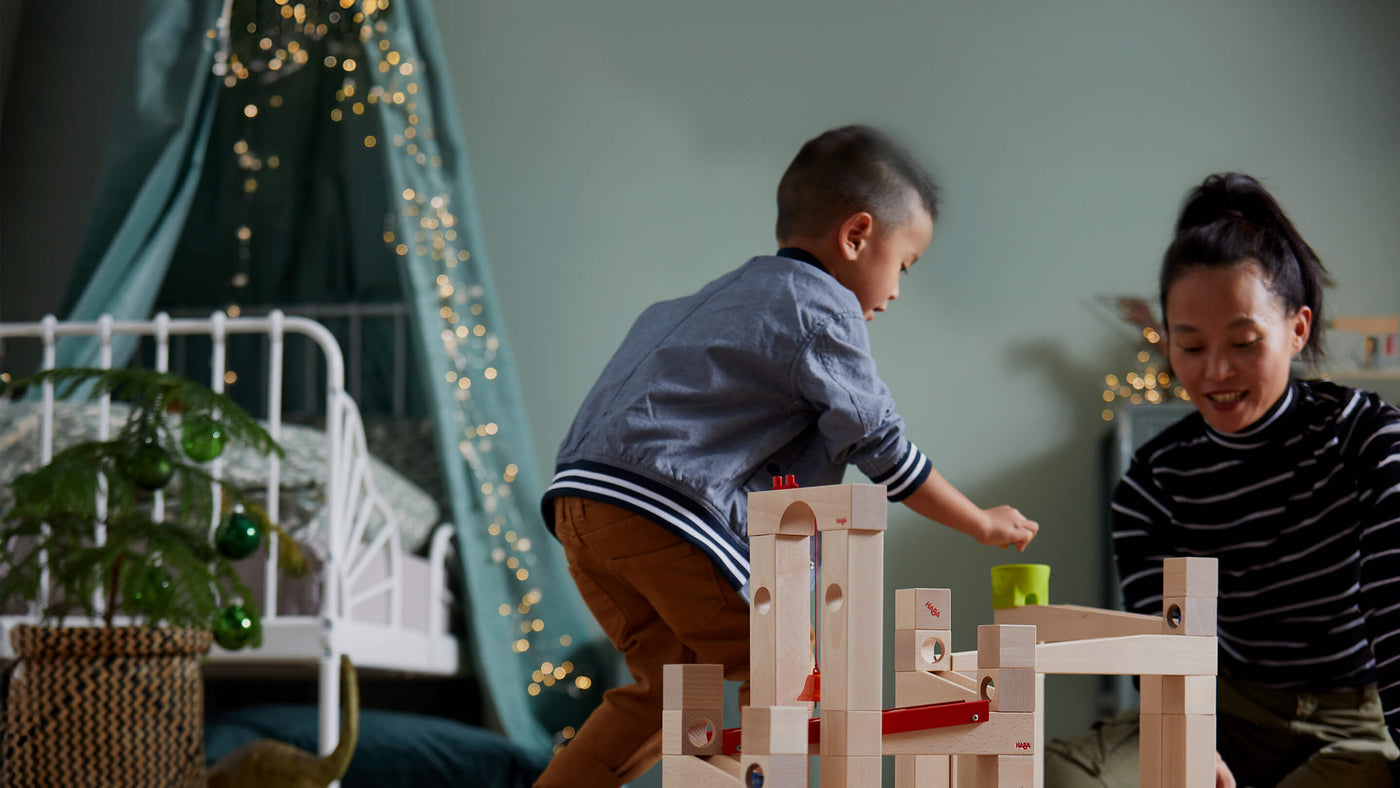 Boy and mom in a bedroom decorated for the holiday playing with HABA Marble Run Large Set