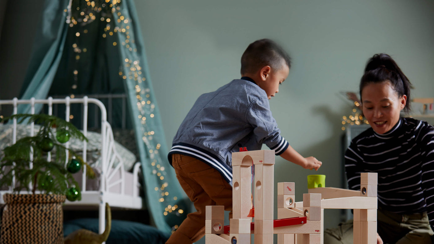 Boy and mom in a bedroom decorated for the holiday playing with HABA Marble Run Large Set