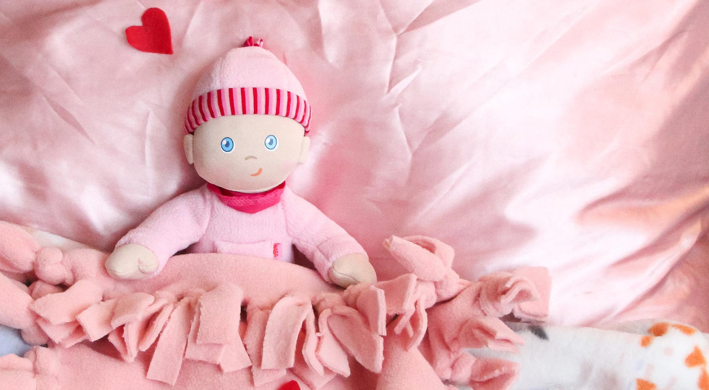 A HABA loisa Soft Doll sits under a DIY pink blanket.