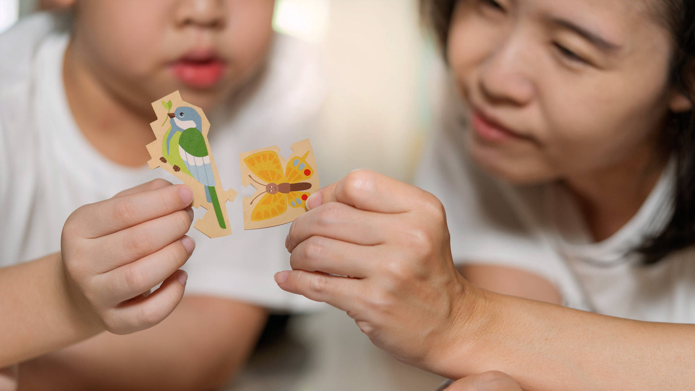  Downloaded Close up of mother and son lying on the floor holding puzzle pieces and putting them together.