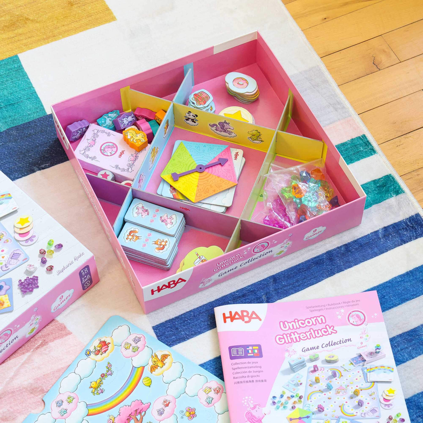 HABA Unicorn Glitterluck Game Collection game box with colorful packaging on a striped rug