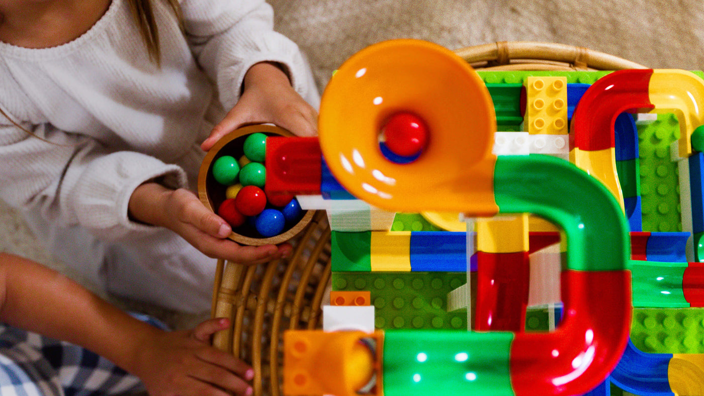 Child playing with a colorful Hubelino marble run toy on a wooden table.