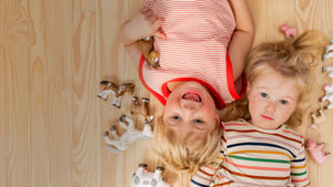 Overhead view of two kids laying on their backs with Little Friends animals surrounding them