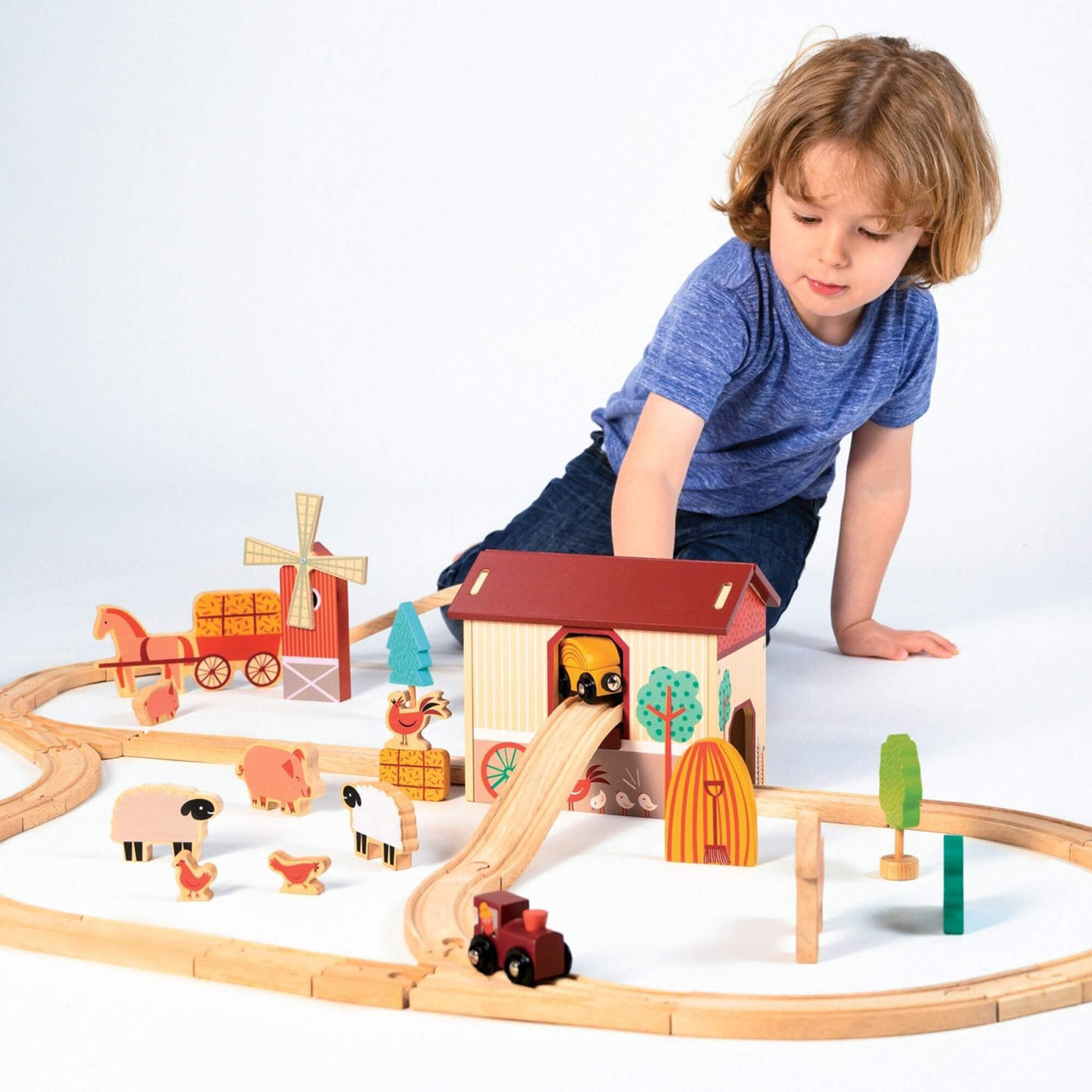 Child playing with a wooden train set on a white background