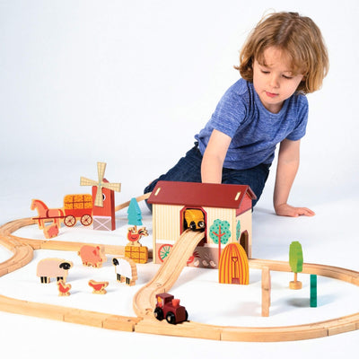 Child playing with a wooden train set on a white background