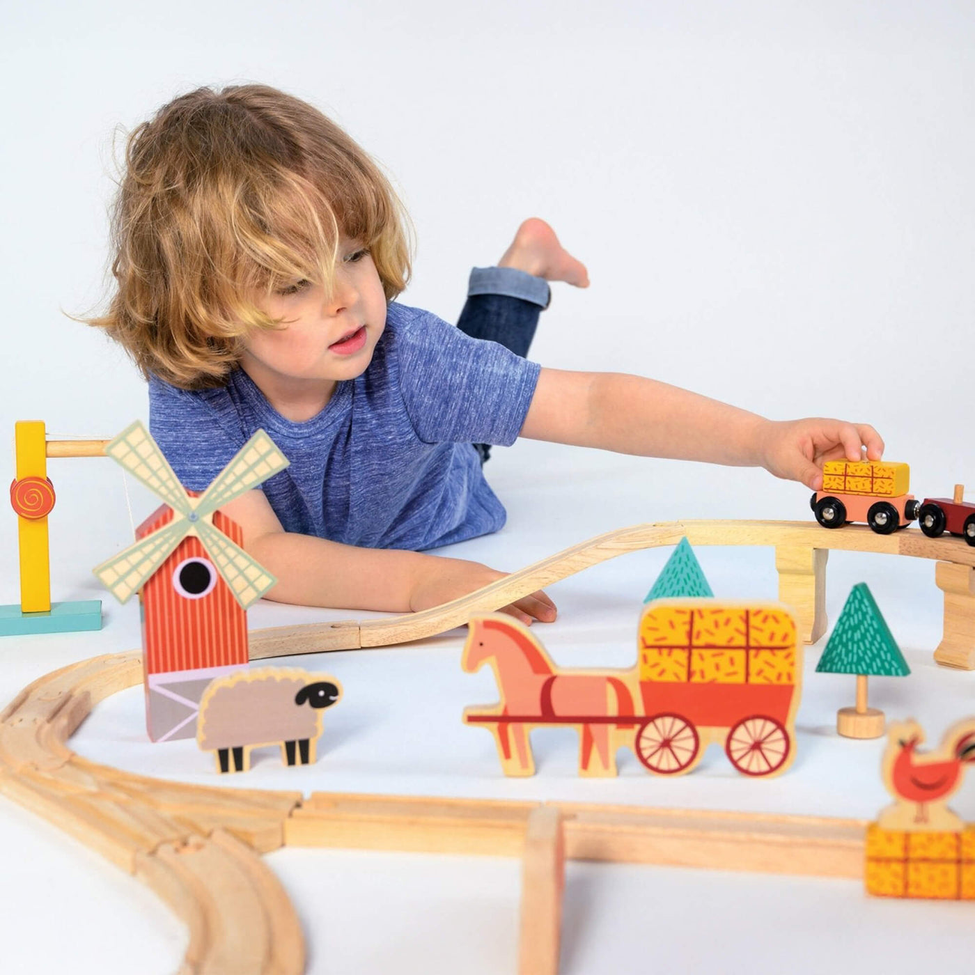 Child playing with a wooden toy train set on a white background