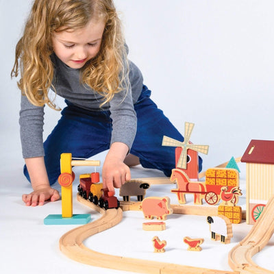 Child playing with a wooden toy train set on a white background