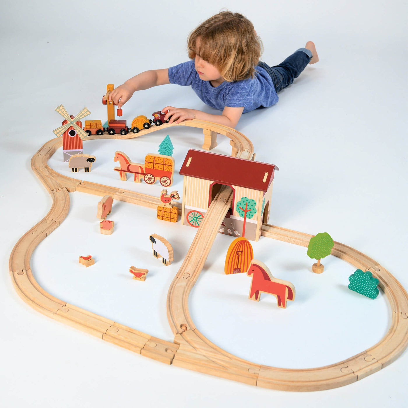 Child playing with a wooden train set on a white background