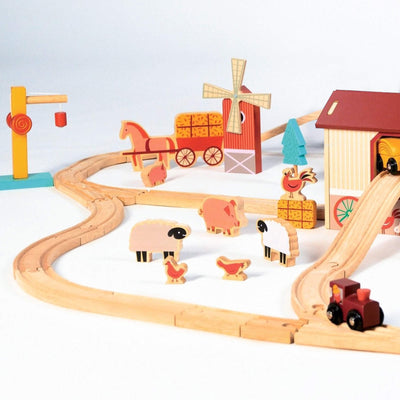 Wooden toy train set with farm-themed tracks, animals, and structures on a white background
