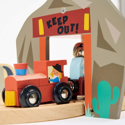 Toy train with a 'Keep Out!' sign on a cardboard gate, featuring a cactus design.
