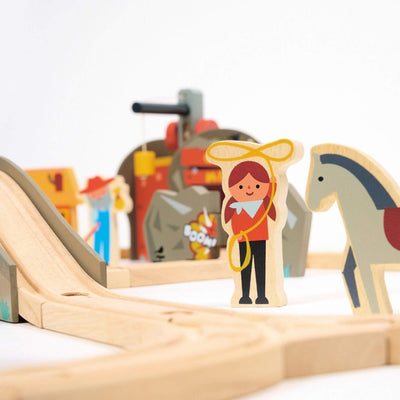 Wooden toy figure of a girl with a horse on a track with blurred toys in the background