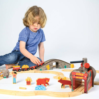 Child playing with a wooden train set on a white background