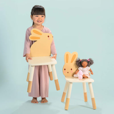 Child holding a large rabbit-shaped chair with a smaller chair and doll on a light blue background