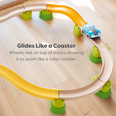Toy track set with a car on a wooden floor, featuring text about how the car sits on top of the tracks so it glides like a roller coaster