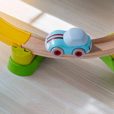 Toy car on a wooden track with colorful connectors on a light wood surface