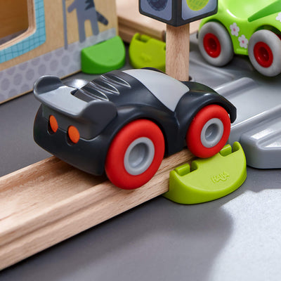 Toy car on a wooden track with a toy traffic light and other toys in the background