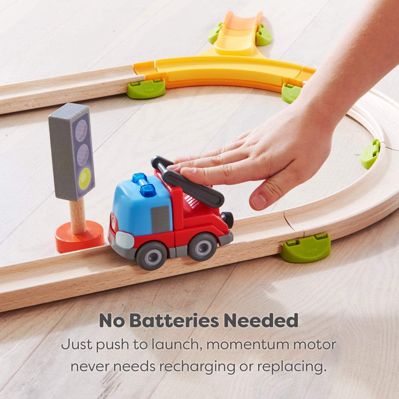 Wooden track set set with a red fire engine on a wooden track, hand pushing with it with text saying no batteries are needed