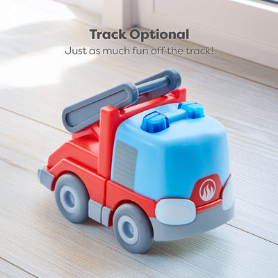 Toy fire truck with red and blue colors on a light wooden surface with the text saying that tracks are optional