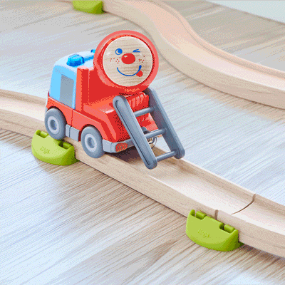 Red ball with a funny face rolling down the ladder of a toy fire truck