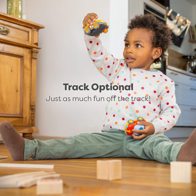 Child playing with HABA Cars on a wooden floor in a home setting with text reading "Track optional, Just as much fun off the track!"