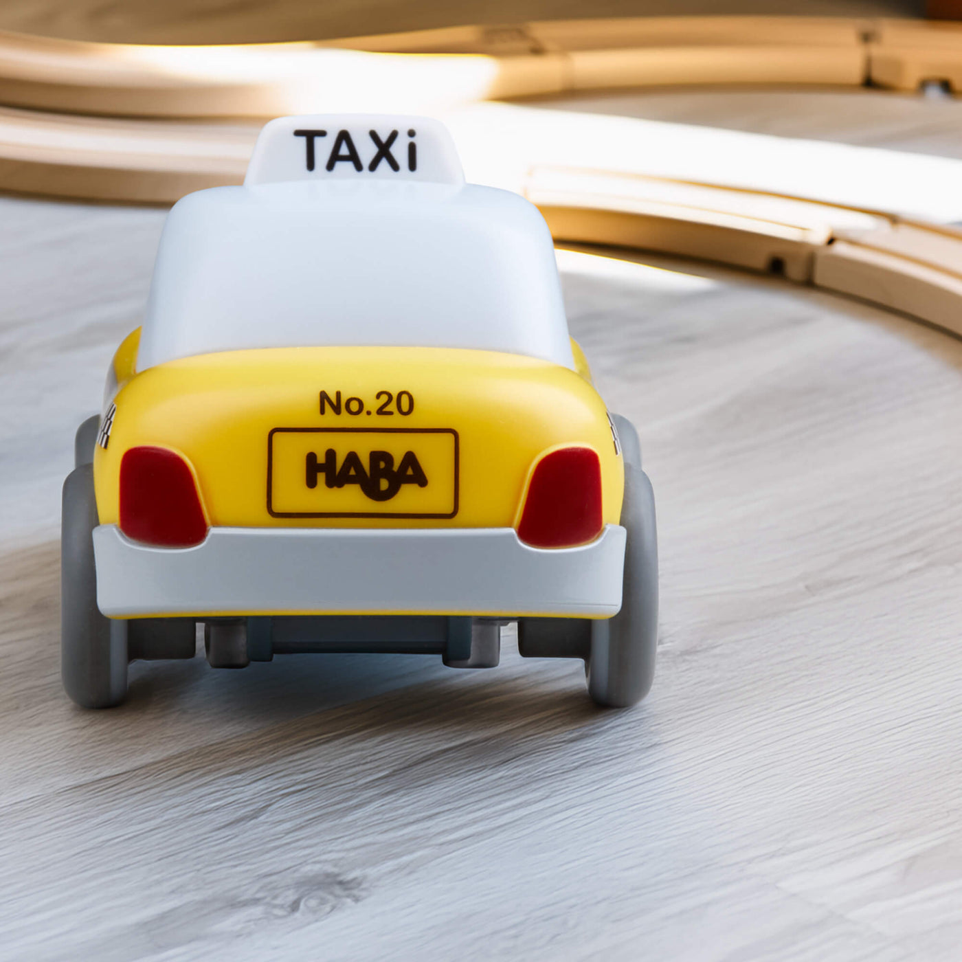 Toy taxi with 'HABA' branding on a wooden track