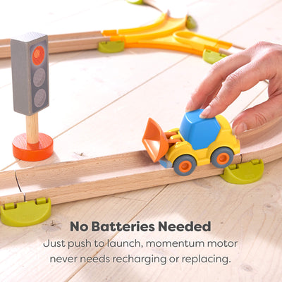 Toy wheel loader on a wooden track with a hand pushing it and text showing how batteries are not needed