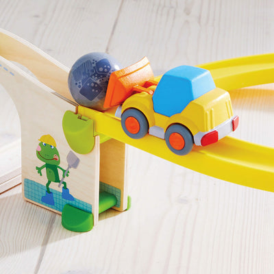 Toy wheel loader pushing a ball on a track.