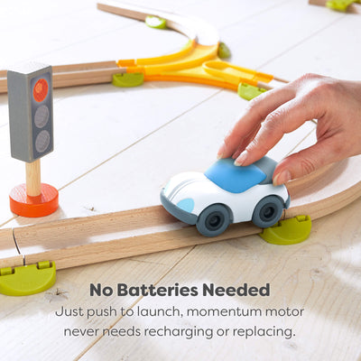 Toy car on a wooden track with a hand pushing it, traffic light in the background with text explaining there are no batteries needed.