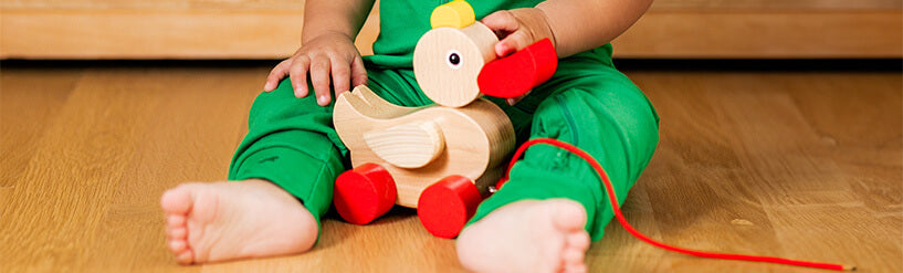 Toddler holding HABA wooden duck pull toy