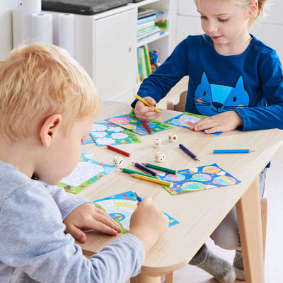 Children playing Color It game by HABA on wooden table