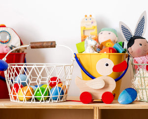 HABA basket with wooden eggs, wooden duck, musical instruments, and doll on top of a playshelf