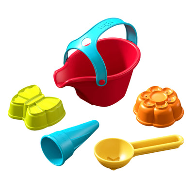 A red sand bucket with a blue handle, surrounded by 2 colorful molds: a yellow butterfly and orange flower, and blue cone, plus a yellow scoop.