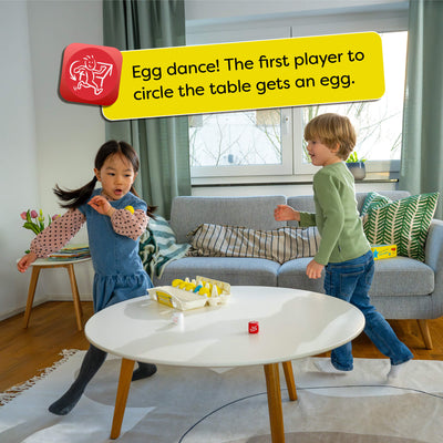 Two children playing a game around a table with HABA Dancing Eggs on it, in a living room setting. Text overlay says "Egg dance! The first player to circle the table gets an egg."
