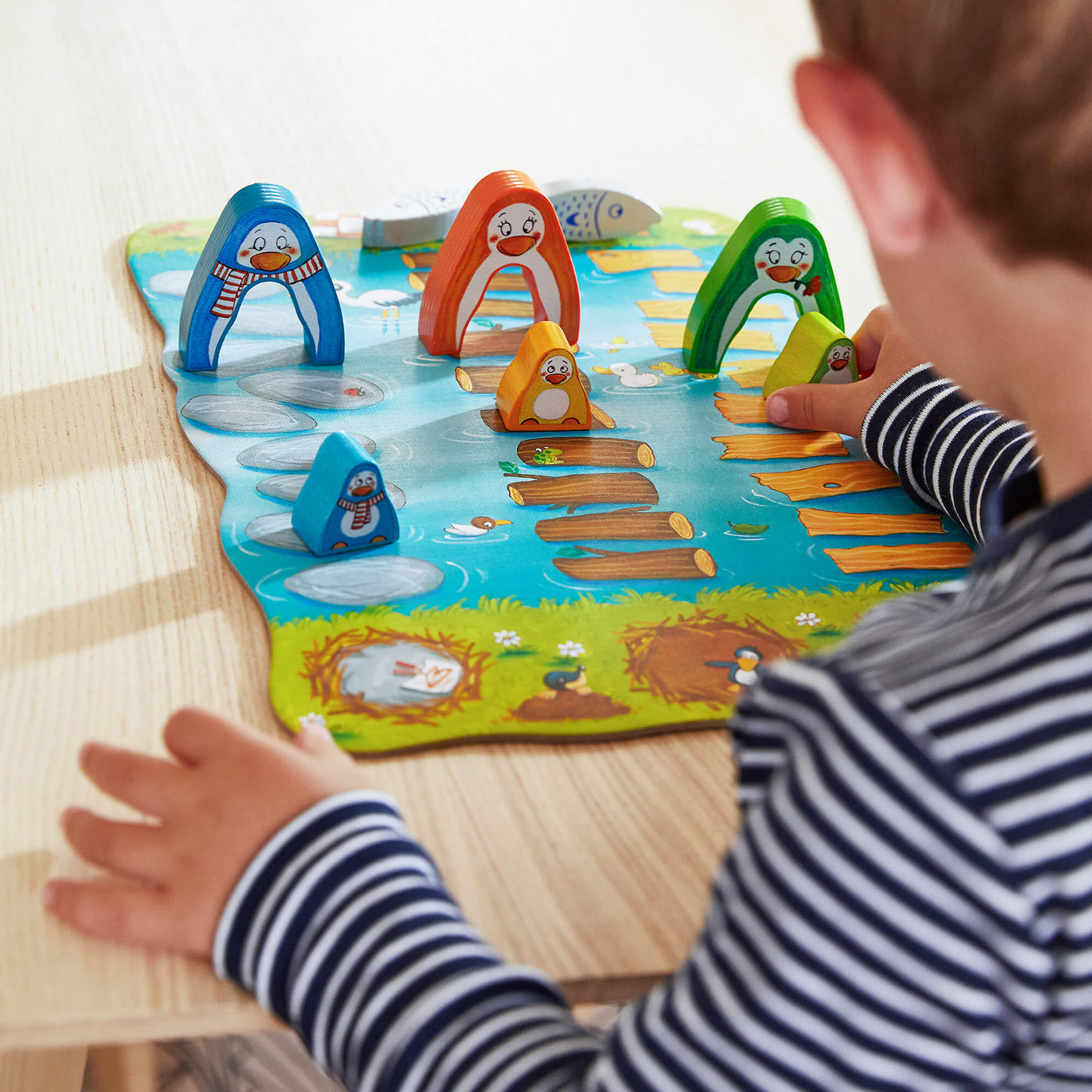 Child playing with My Very First Games Go Go Little Penguin wooden toy penguin pieces setup on a table