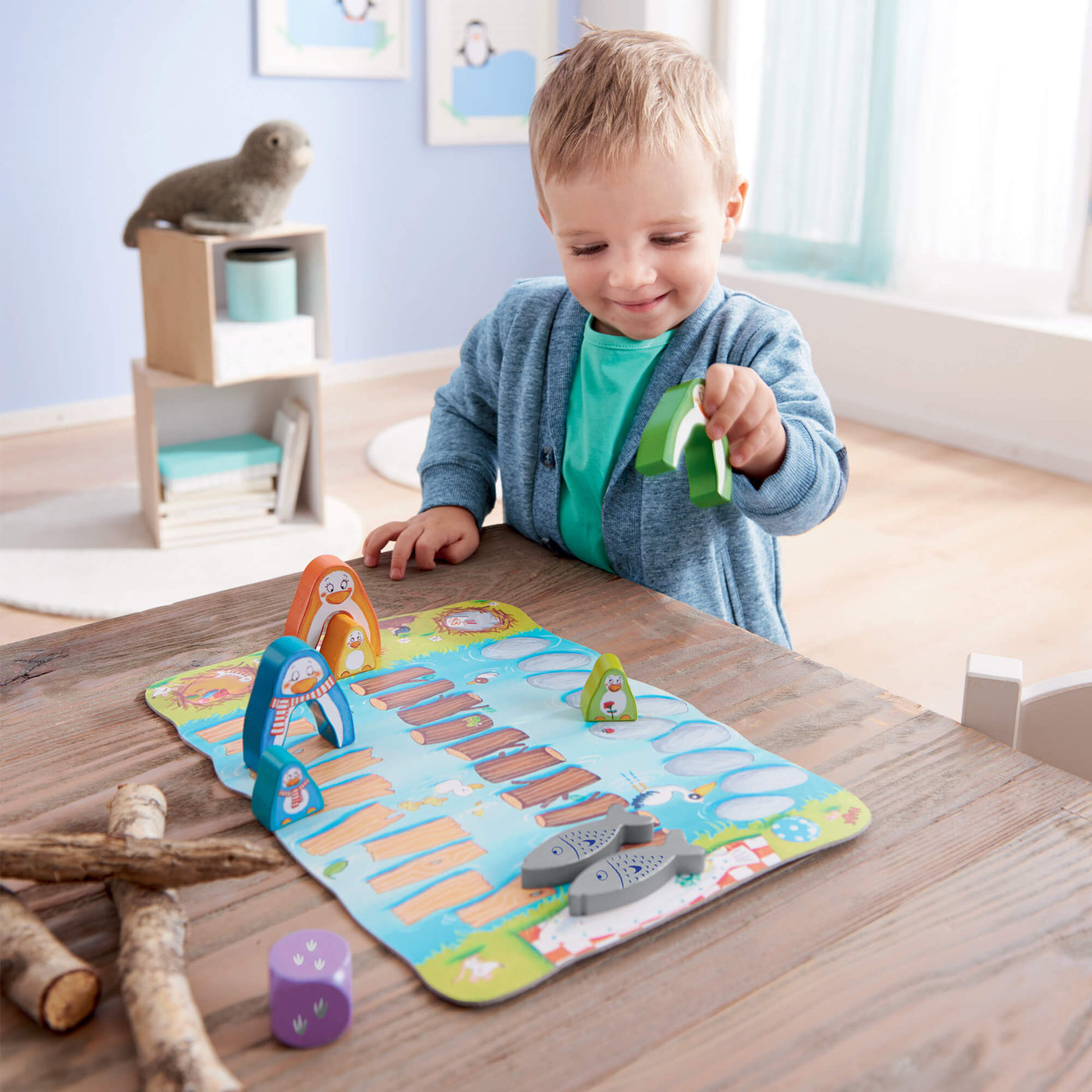 Child playing with My Very First Games Go Go Little Penguin animal pieces on a wooden table.