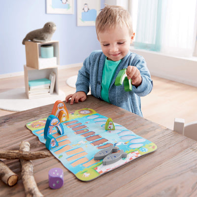Child playing with My Very First Games Go Go Little Penguin animal pieces on a wooden table.