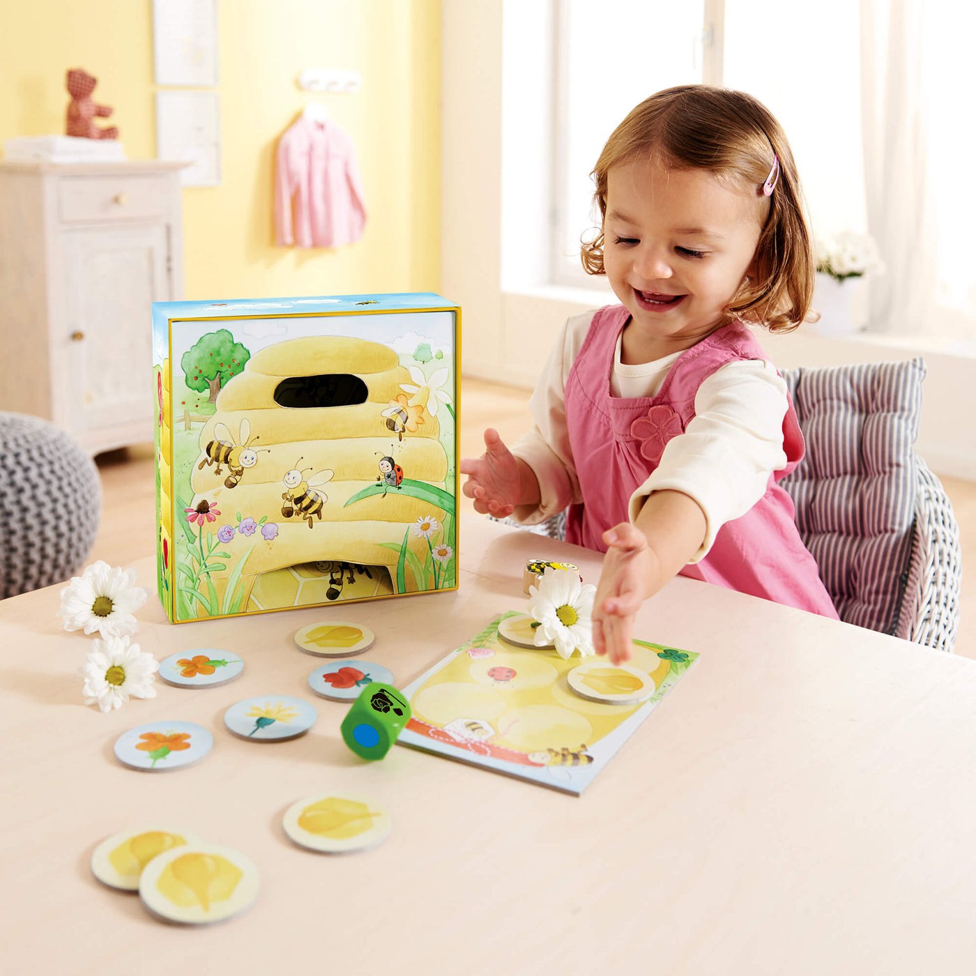 Girl rolling green wooden die playing Hanna Honeybee from HABA